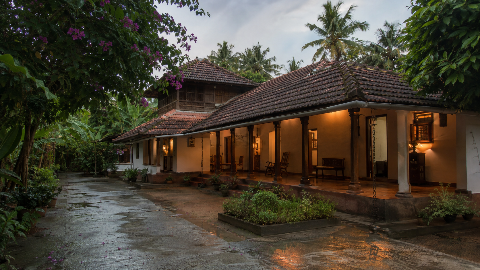 A traditional tiled-roof private home with a tropical Kerala courtyard after rain